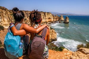 Travel Scenery with Friends - two women with one arm around each other staring out over a cliff into the ocean